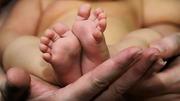 pieds de bébé dans la main de la mère  | Photographie de nouveau-né